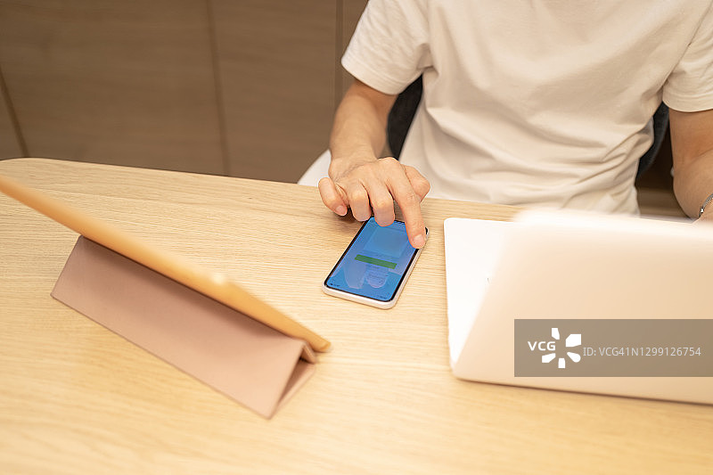 男子在电脑旁使用手机图片素材