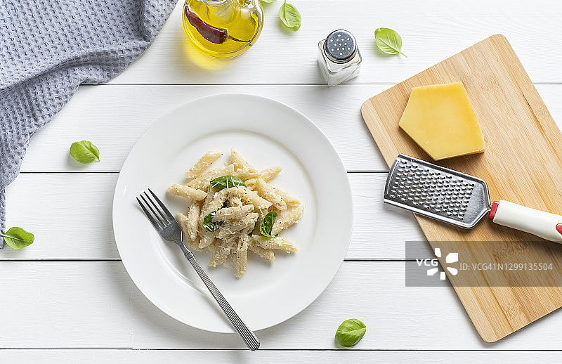在家烹饪奶油罗勒意大利面：将帕尔马干酪磨碎并加入意面中，纯素食品，分步教学第11步。图片素材