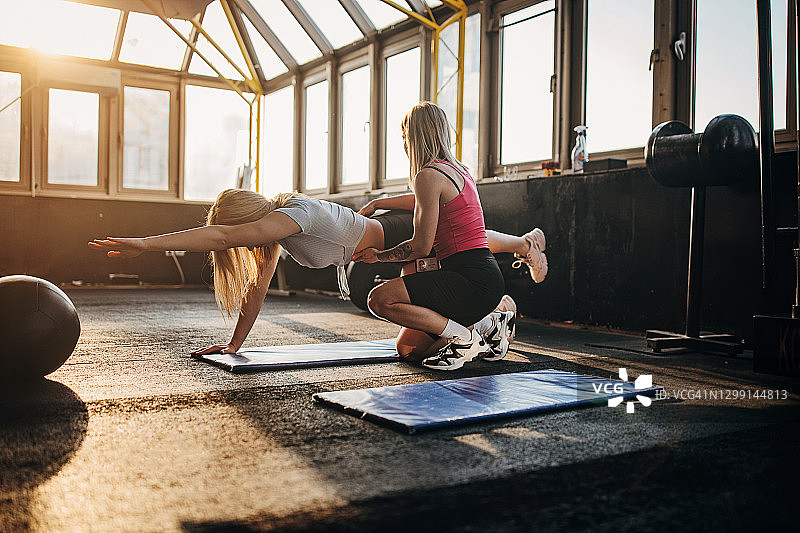 女性健身教练指导年轻女子锻炼图片素材