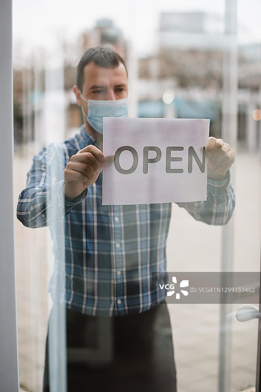 店主戴着口罩在咖啡馆开门图片素材