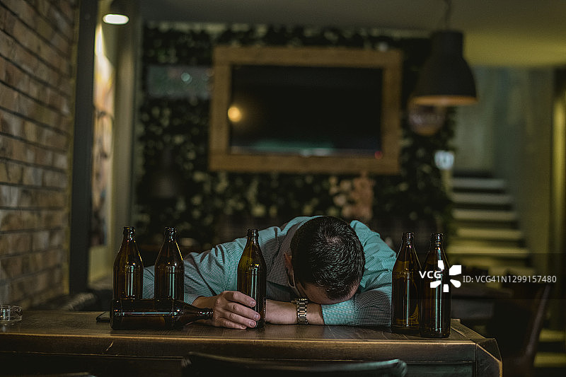 年轻醉酒男子在吧台睡觉图片素材