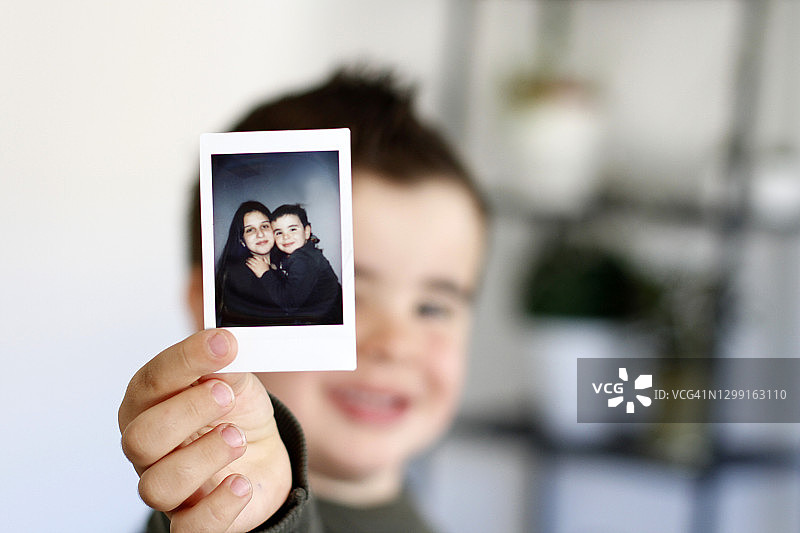 男孩向相机展示即时照片图片素材