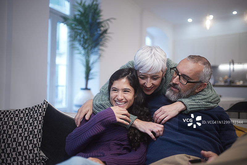 老年母亲在家中沙发上拥抱女儿和丈夫图片素材