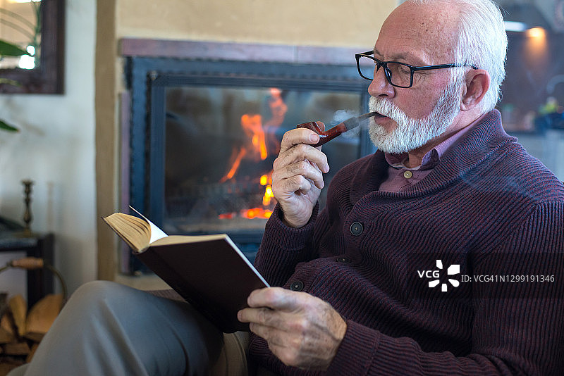 老年男人在壁炉前看书图片素材