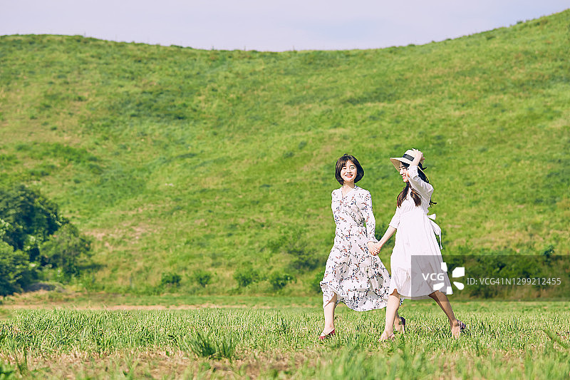 两名女子在绿色田野上行走图片素材