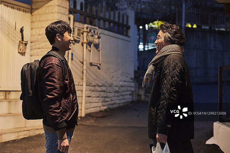 夜晚小巷里的中年男人和儿子图片素材