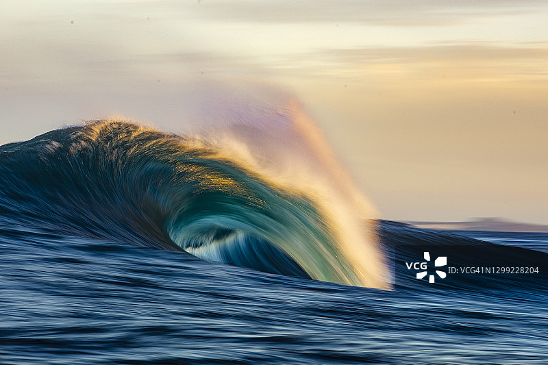 金色晨光中破碎的波浪图片素材