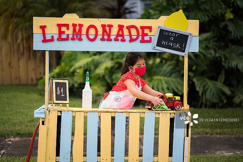 小女孩戴着口罩为柠檬水摊位消毒图片素材