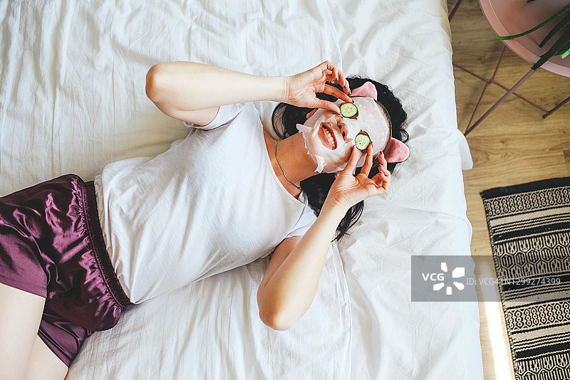 在床上敷着黄瓜面膜的睡衣女孩图片素材