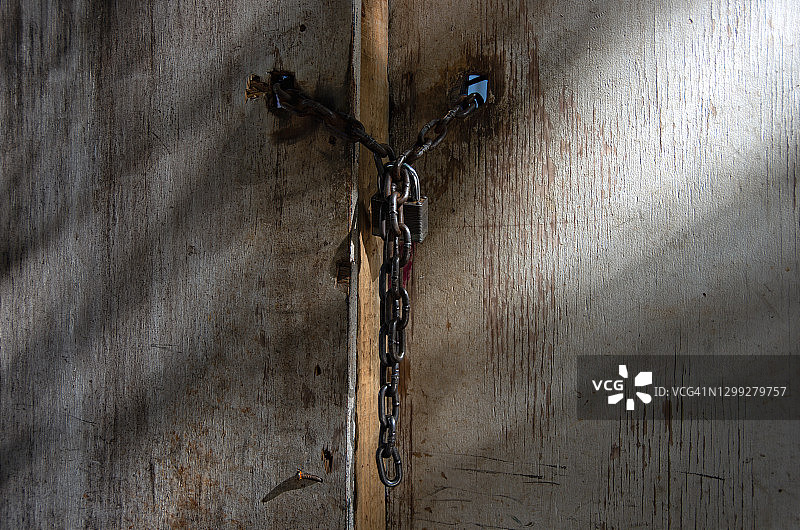 风化胶合板门上的挂锁和链条图片素材