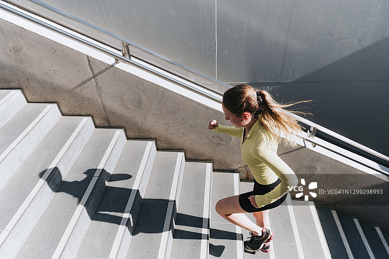 在城市户外跑步上楼梯的年轻运动女性图片素材