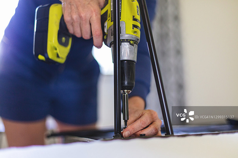 中年妇女使用无绳电钻组装图片素材