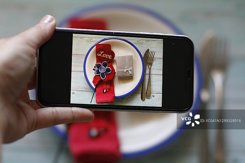 拍摄情人节餐桌布置照片的女人图片素材