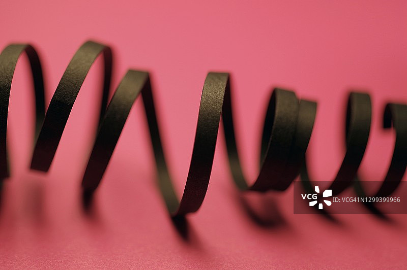 粉色背景上的黑色卷曲丝带图片素材