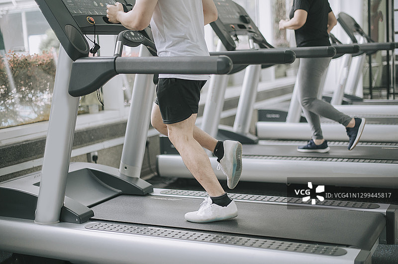 亚洲男女在健身中心日常跑步机锻炼图片素材