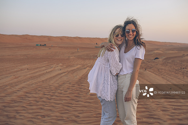 在开阔的沙漠地区暂停休息，微笑的女性朋友们图片素材