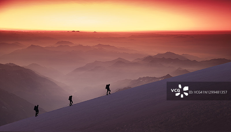 日出时分雪岭上的登山者图片素材