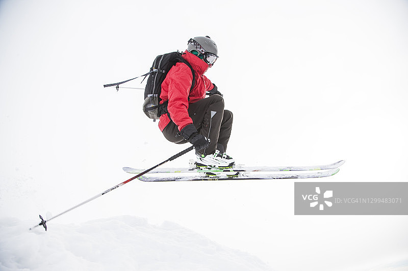 在雪崖上跳跃的滑雪者图片素材