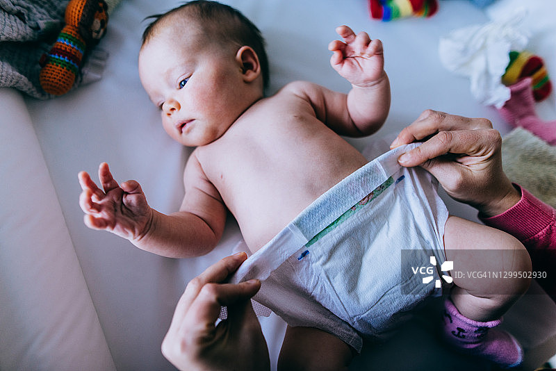 母亲在换尿布台上给宝宝换尿布图片素材