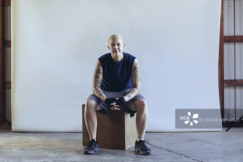 短发健壮女子坐在白色背景的箱子上图片素材