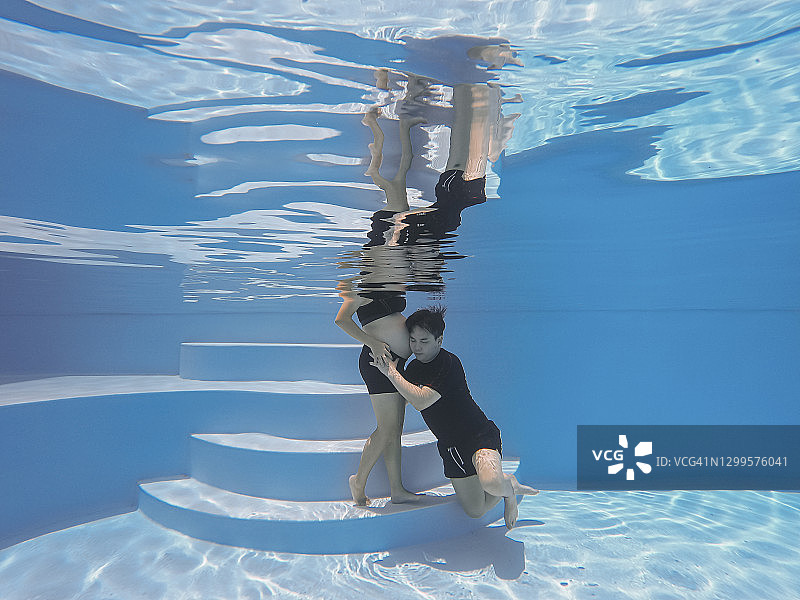 中国男子在泳池中倾听妻子腹中胎儿的声音图片素材