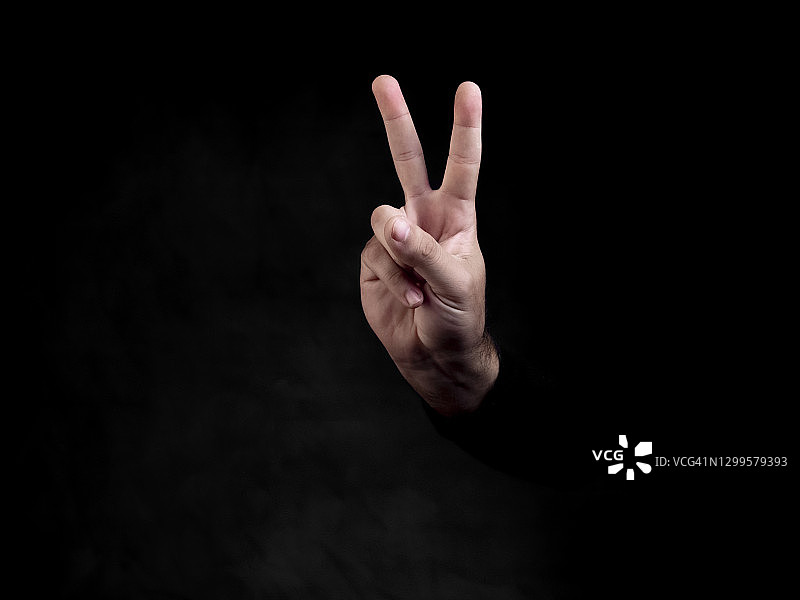 成年男子在黑色背景下手举V字图片素材