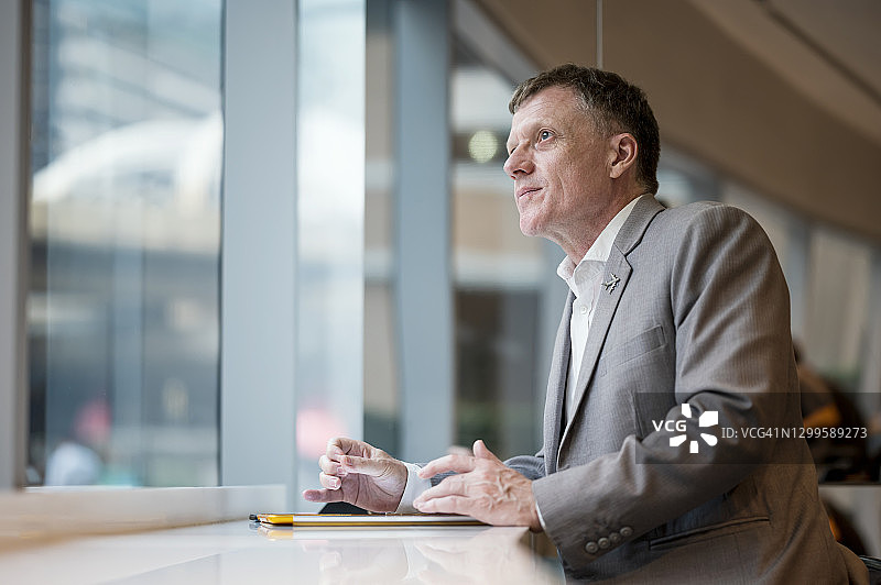 成功的年长商人在酒店休息室的咖啡馆里，看着窗外图片素材