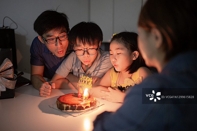 中国家庭为孩子庆祝生日，一起吹蜡烛图片素材