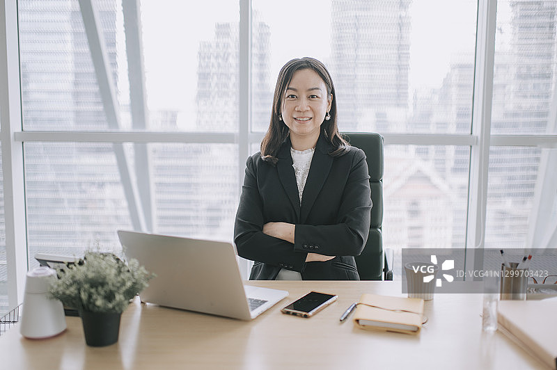 在办公室办公桌前微笑的华人美女CEO高管图片素材