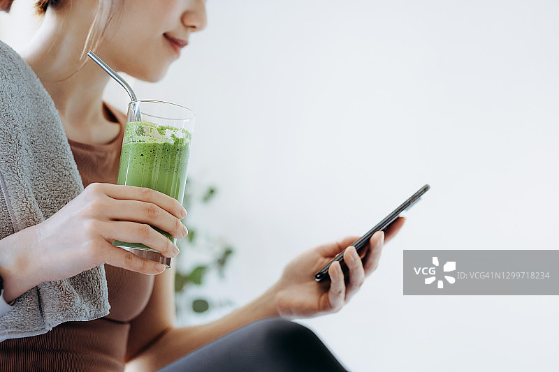 自信亚洲女运动员居家健身后用手机图片素材