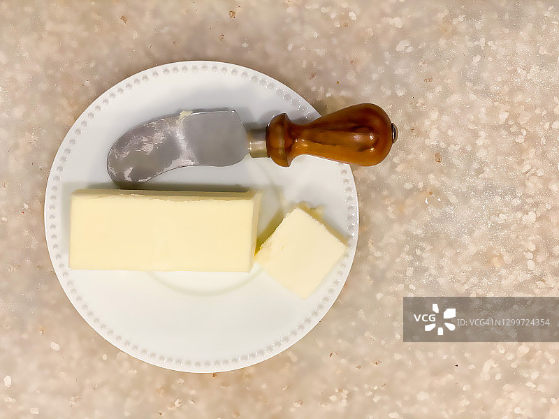 白色背景下，白色小盘子里的黄油条和黄油刀图片素材