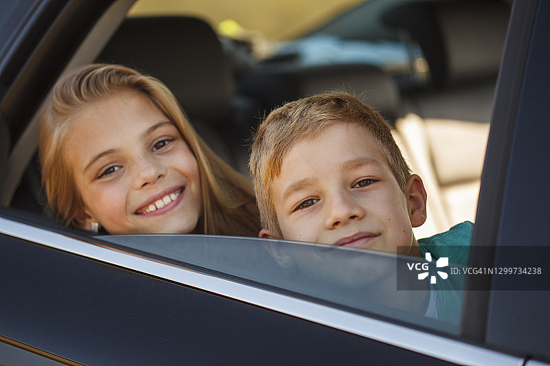 坐在车里对着镜头微笑的兄弟姐妹图片素材