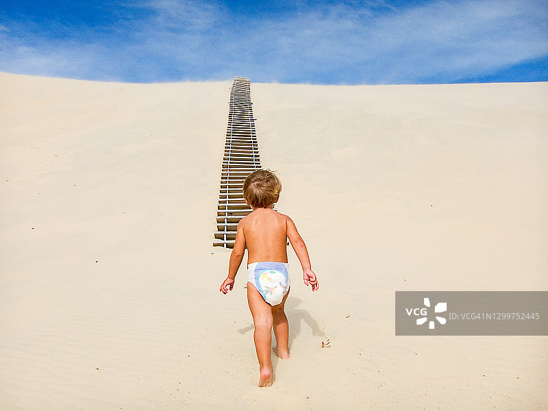 看着沙丘上梯子的幼儿图片素材
