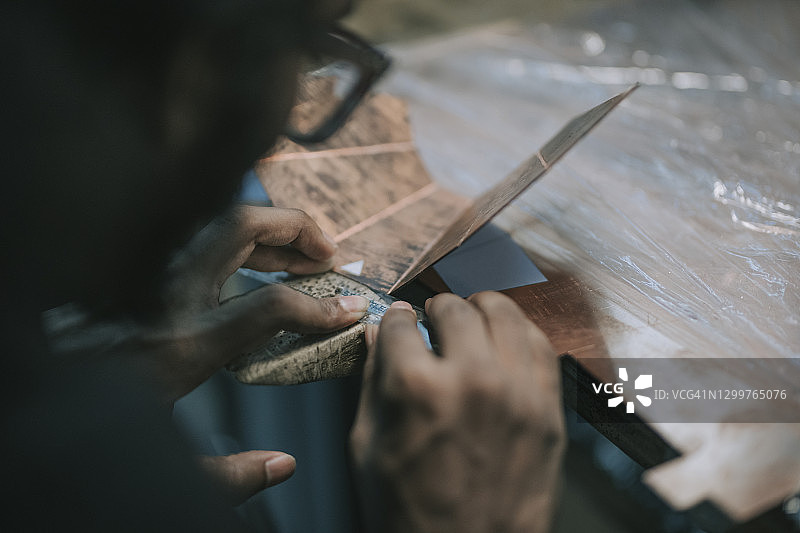 亚洲男学生在大学工作台上制作金属工艺品图片素材