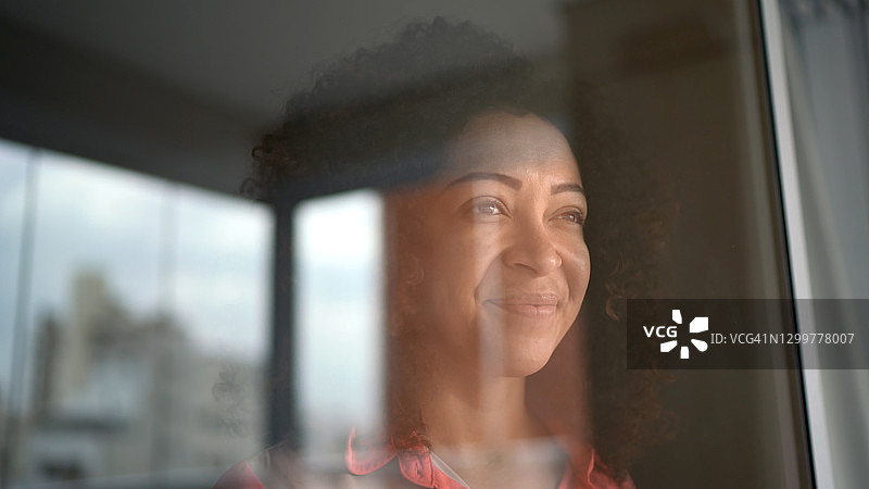 在家透过窗户向外看的中年女人图片素材