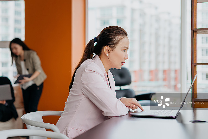 在办公室用笔记本电脑工作的亚洲女商人图片素材