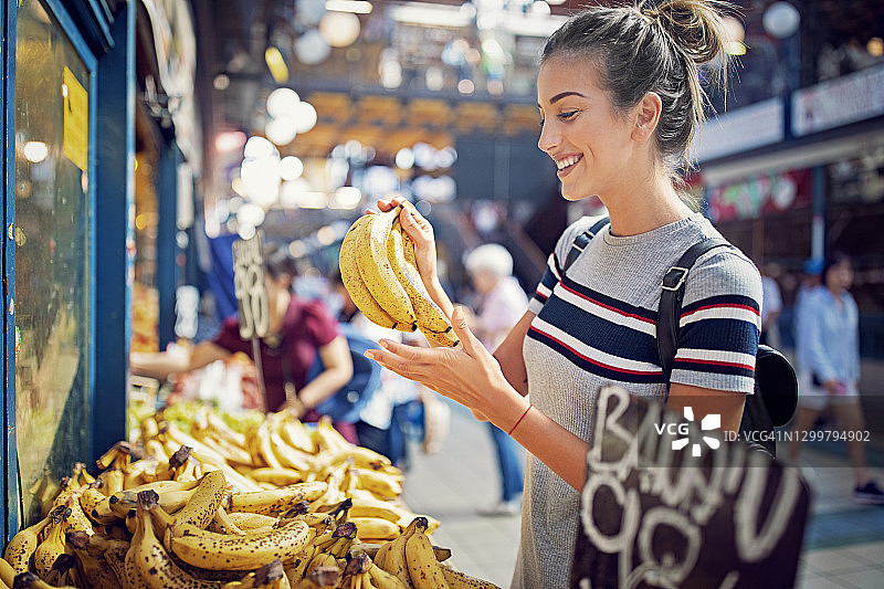 年轻女子在市场上购买香蕉图片素材