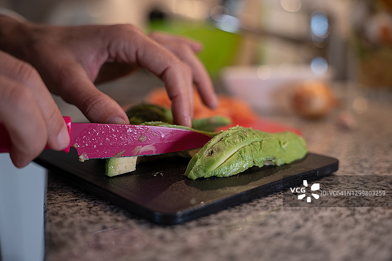 女人在家中厨房切鳄梨的特写图片素材