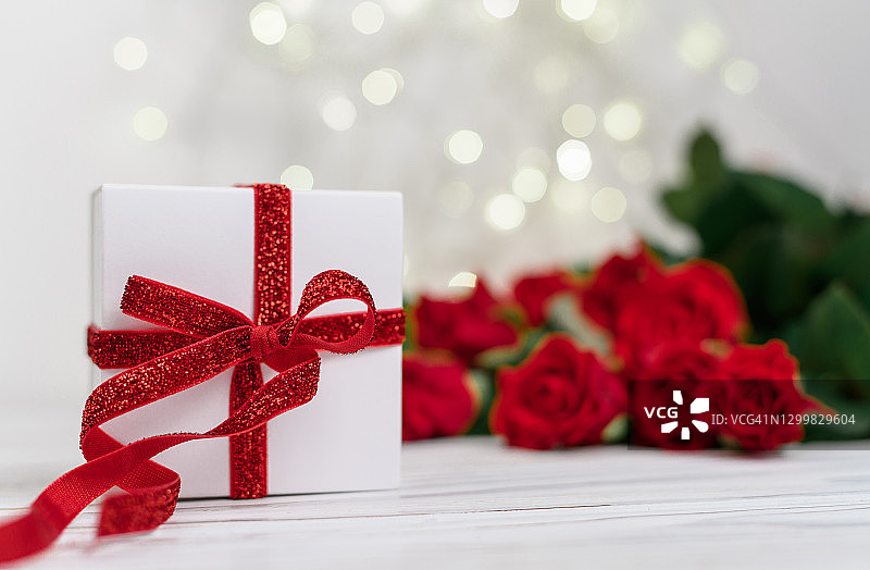 红色玫瑰和散景背景上的红色丝带白色礼品盒，母亲节图片素材