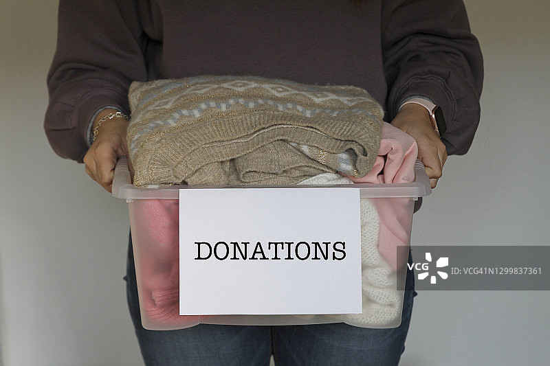 女人拿着衣服放在捐赠箱里图片素材