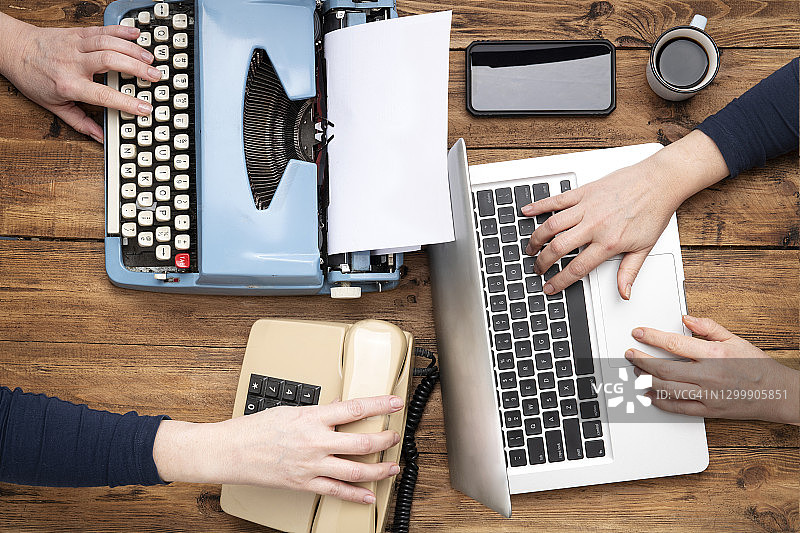 女人在办公桌上用打字机和笔记本电脑打字的手部特写图片素材