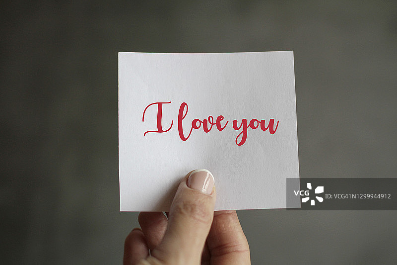 手持写有“我爱你”信息的纸张特写图片素材