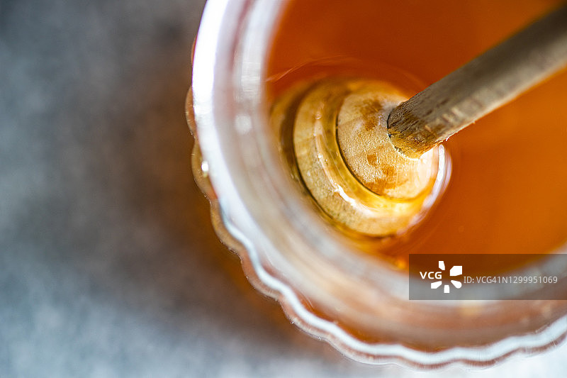 玻璃杯里的有机蜂蜜和蜂蜜勺图片素材