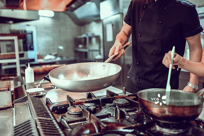 厨师在现代餐厅厨房准备炒饭和酱汁图片素材