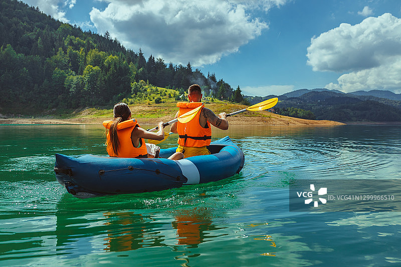 情侣穿着救生衣在湖上划皮划艇图片素材