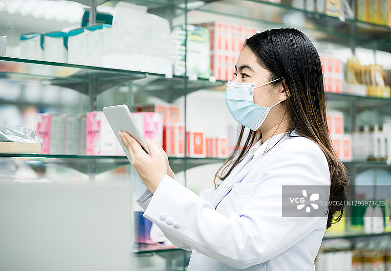 亚洲女药剂师在药店用平板电脑准备库存盘点，以出售给患者图片素材