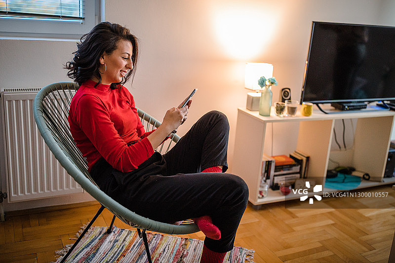 年轻女人在家中给朋友发短信图片素材