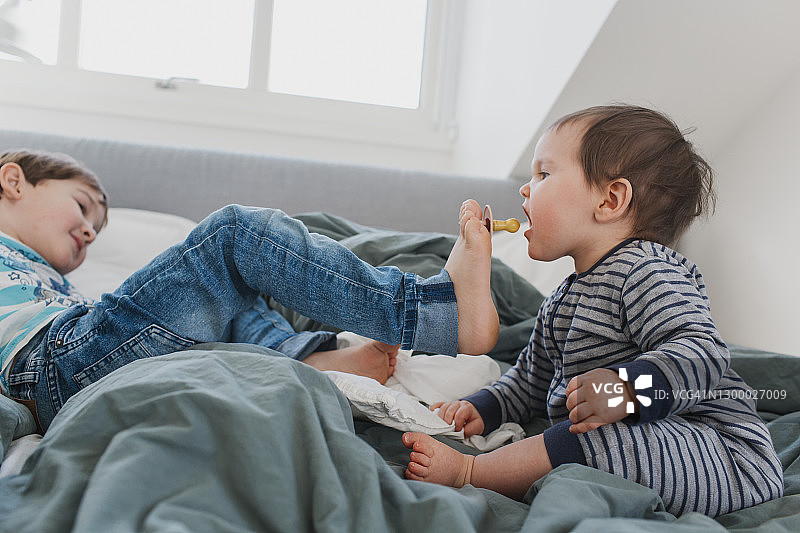 哥哥给蹒跚学步的妹妹喂奶嘴图片素材