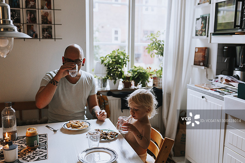 父亲和幼儿在餐桌上用餐图片素材