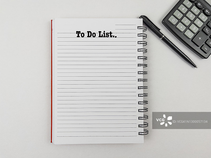 办公桌上的待办事项清单、计算器、鲜花和笔图片素材